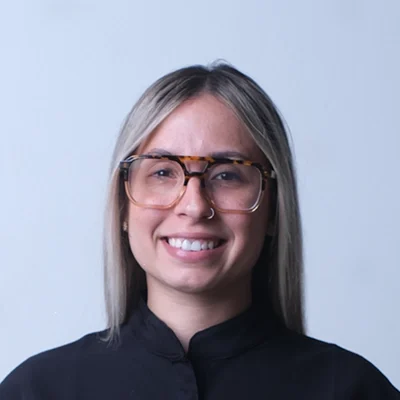 Chiropractor Sayonara M. Rivera Aviles Smiling In Front Of Light Blue Wall